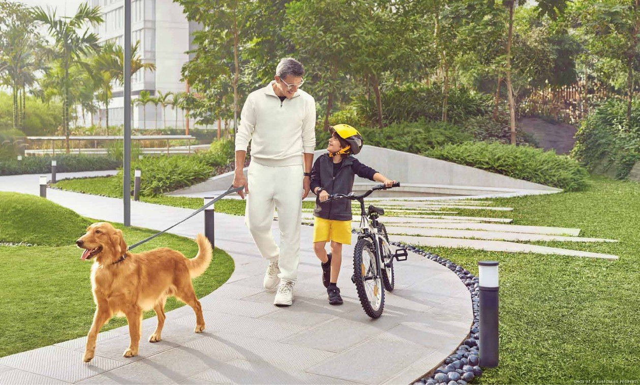 Man walking in lush garden holding a dog in one hand and child’s bicycle in the other at a premium residence in Bandra West.